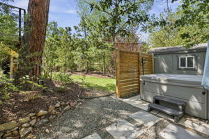 Hot tub set inside a private fenced area, framed by mature trees.