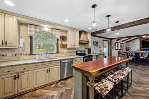 This kitchen has all of the rustic charm paired with 42 inch cabinets, a custom hood, a sizable food pantry, and a wine or coffee station with mini beverage fridge.