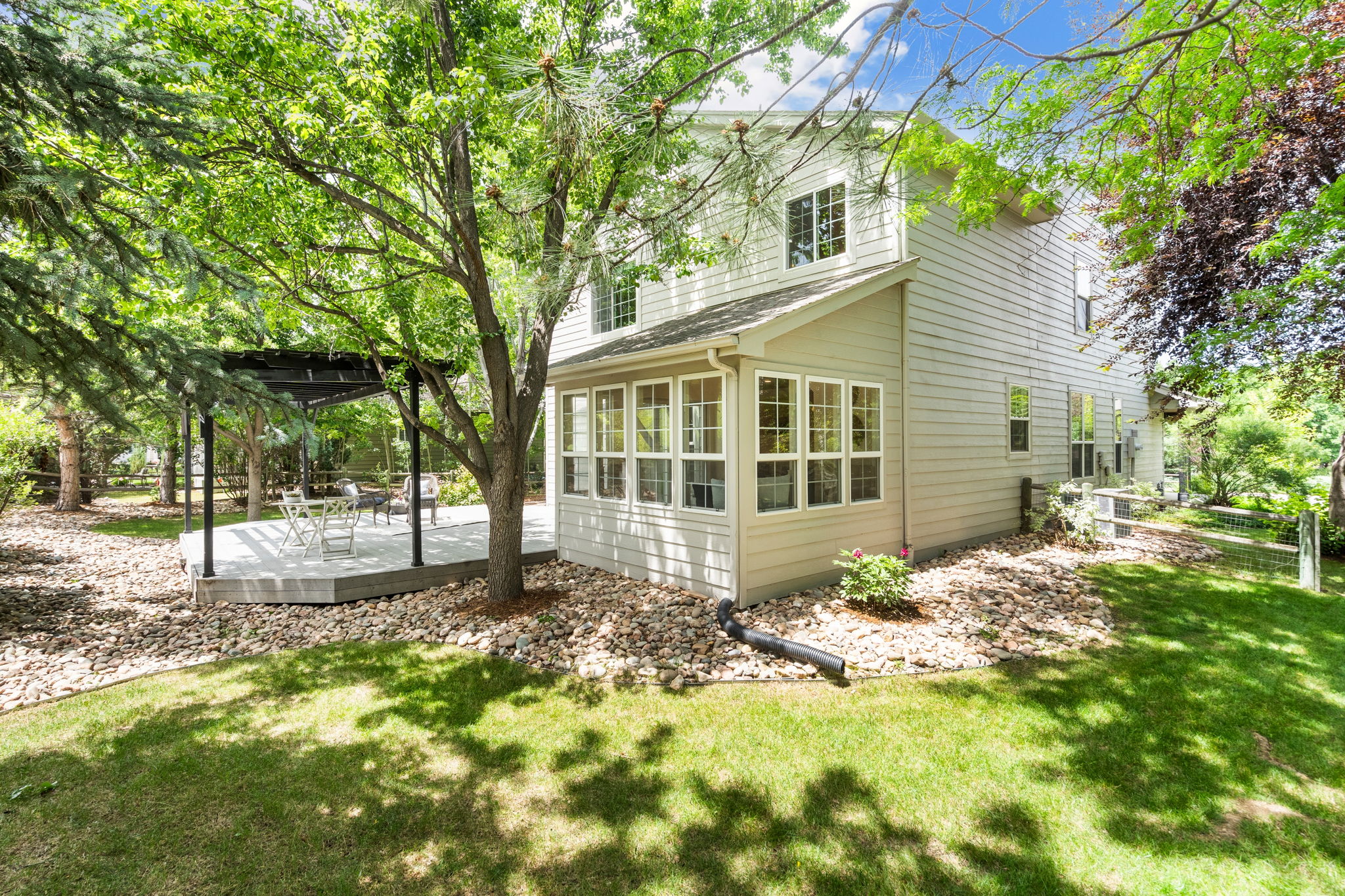 What a beautiful backyard view of one side of the house showing you the sunroom, side yard, and large deck.