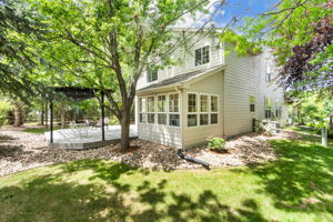 What a beautiful backyard view of one side of the house showing you the sunroom, side yard, and large deck.