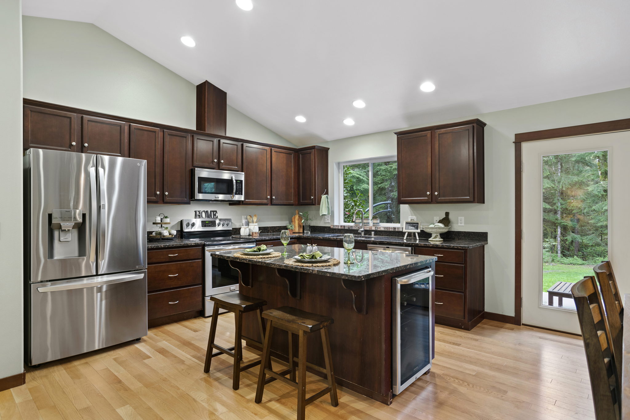Stainless Steel appliances, gorgeous dark wood cabinetry, bar seating and built in wine fridge make this a Chefs dream kitchen!