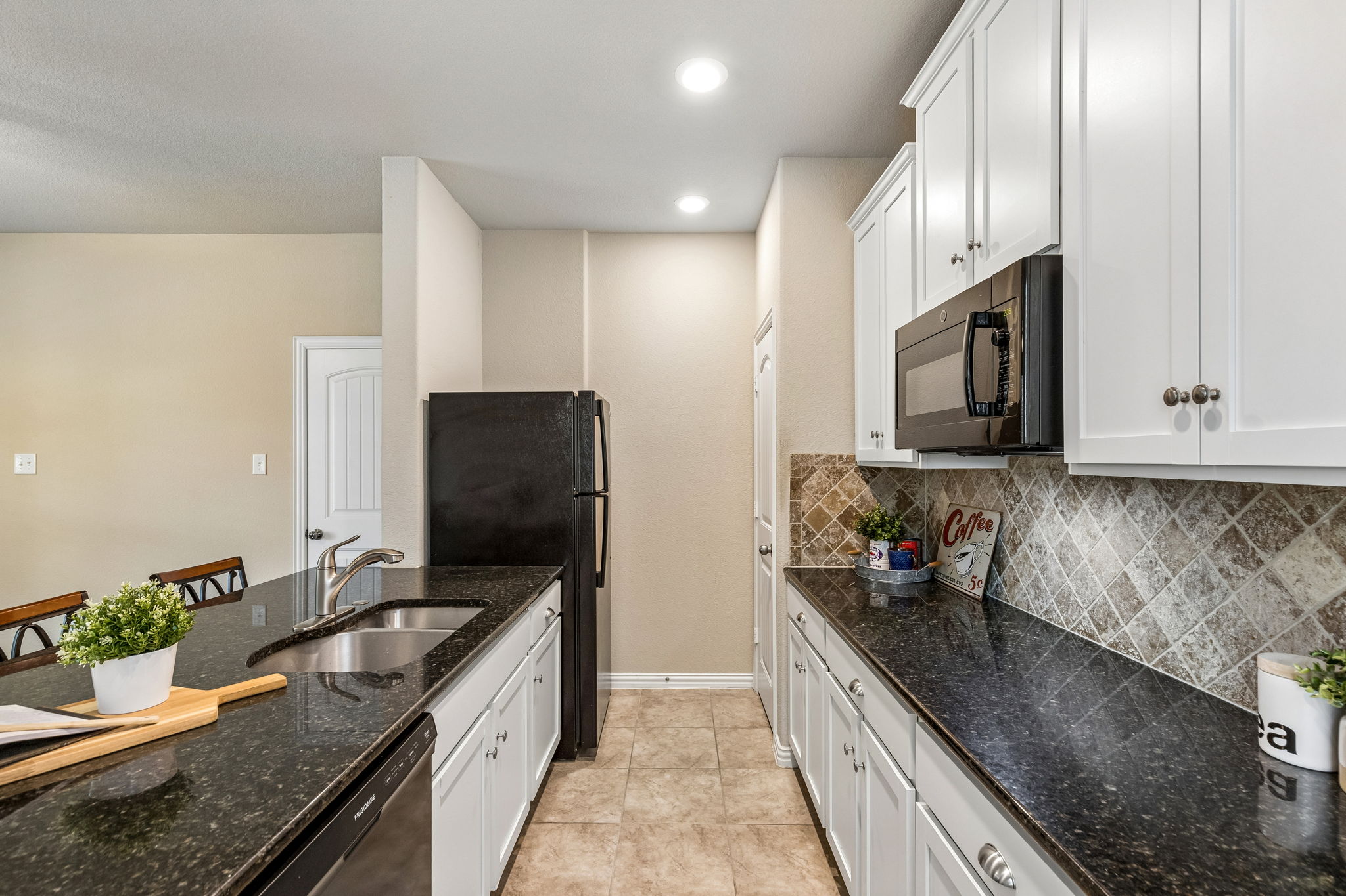 Separate Mother-In-Law Apartment with kitchenette featuring granite counters, a pantry, deep sink, white cabinets, and a microwave