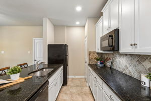 Separate Mother-In-Law Apartment with kitchenette featuring granite counters, a pantry, deep sink, white cabinets, and a microwave