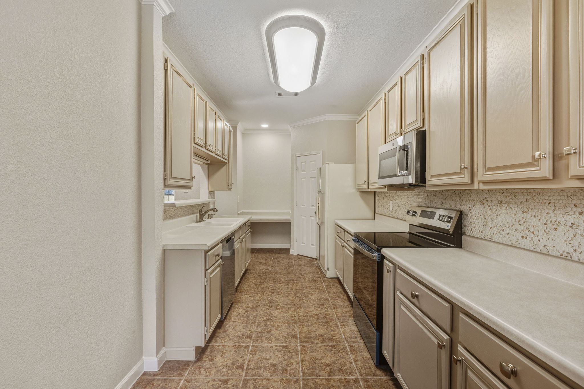 Bright and functional kitchen featuring newly painted cabinets, generous counter space and a charming coffee bar or desk area next to a walk-in pantry.