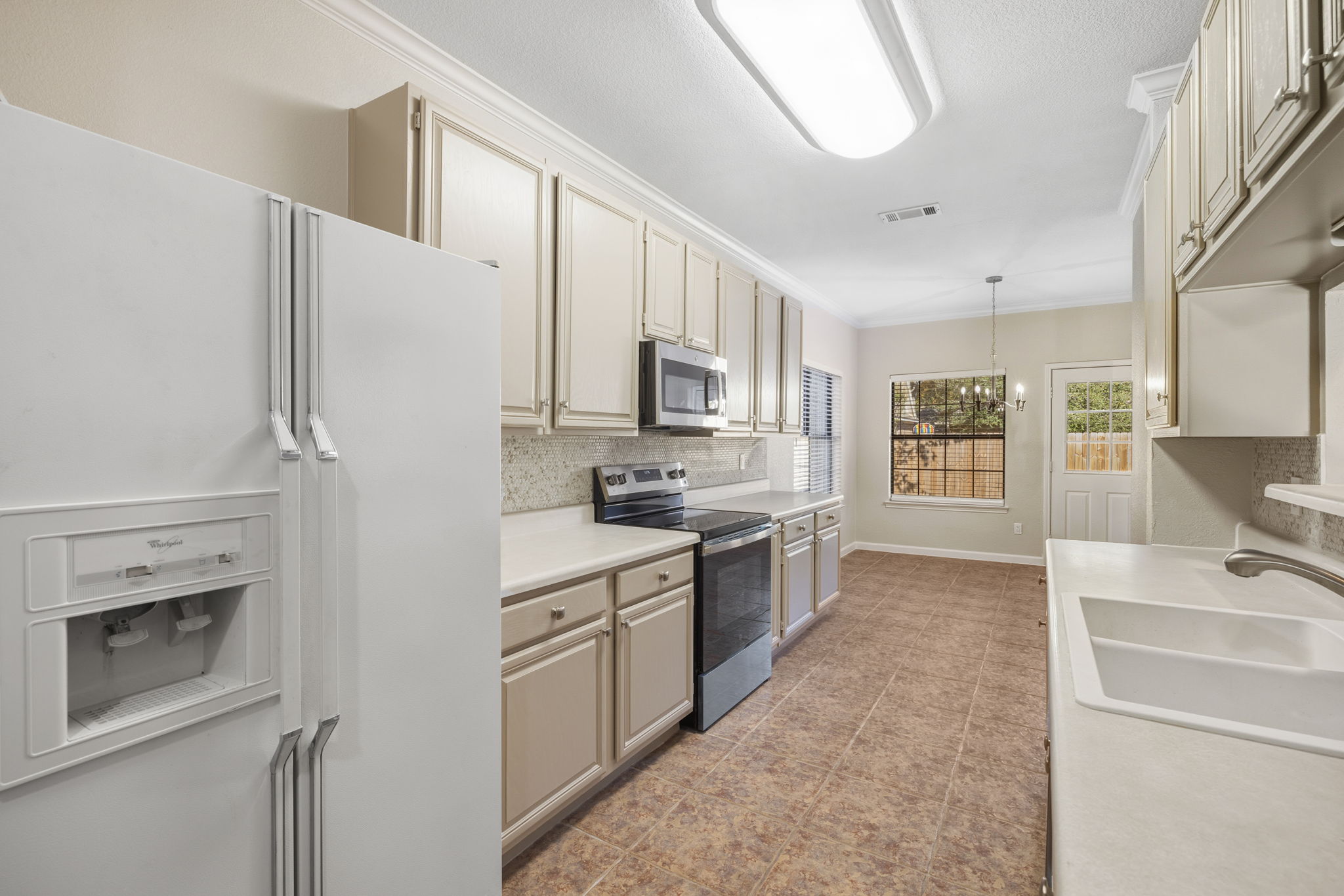 Bright and functional kitchen featuring newly painted cabinets, generous counter space for everyday cooking or entertaining, and a charming breakfast nook overlooking the backyard.