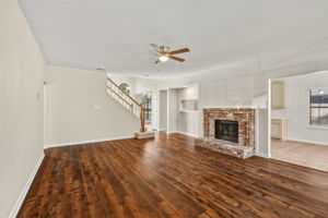 Expansive family room showcasing sightlines to the front entry and stairs, unified by continuous luxury vinyl flooring.