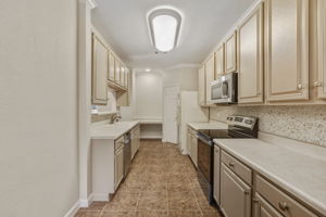Bright and functional kitchen featuring newly painted cabinets, generous counter space and a charming coffee bar or desk area next to a walk-in pantry.