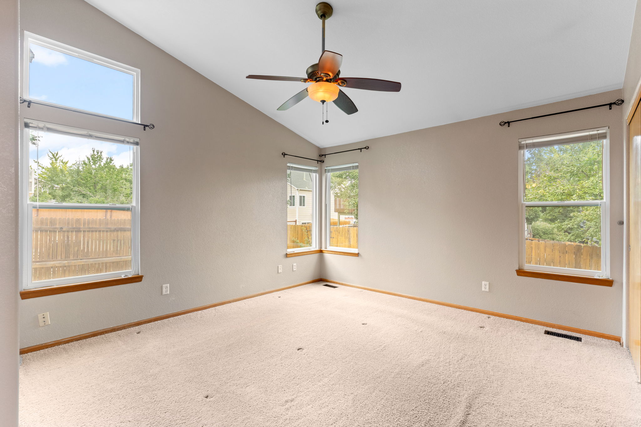 Vaulted primary bedroom with clerstory window