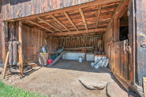 Inside this historic barn: covered feeding area with horse stalls & hay storage are to the right & left