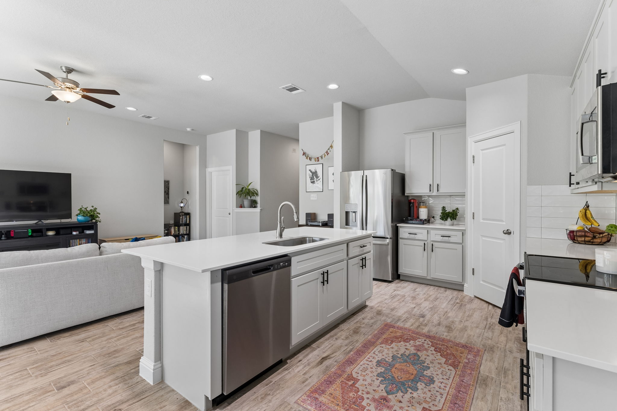 White cabinetry, stainless steel appliances, and tile backsplash