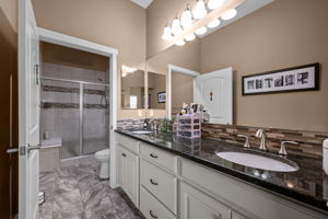 Private Primary Bathroom with slab granite counters, 2 sinks, ceramic tile flooring