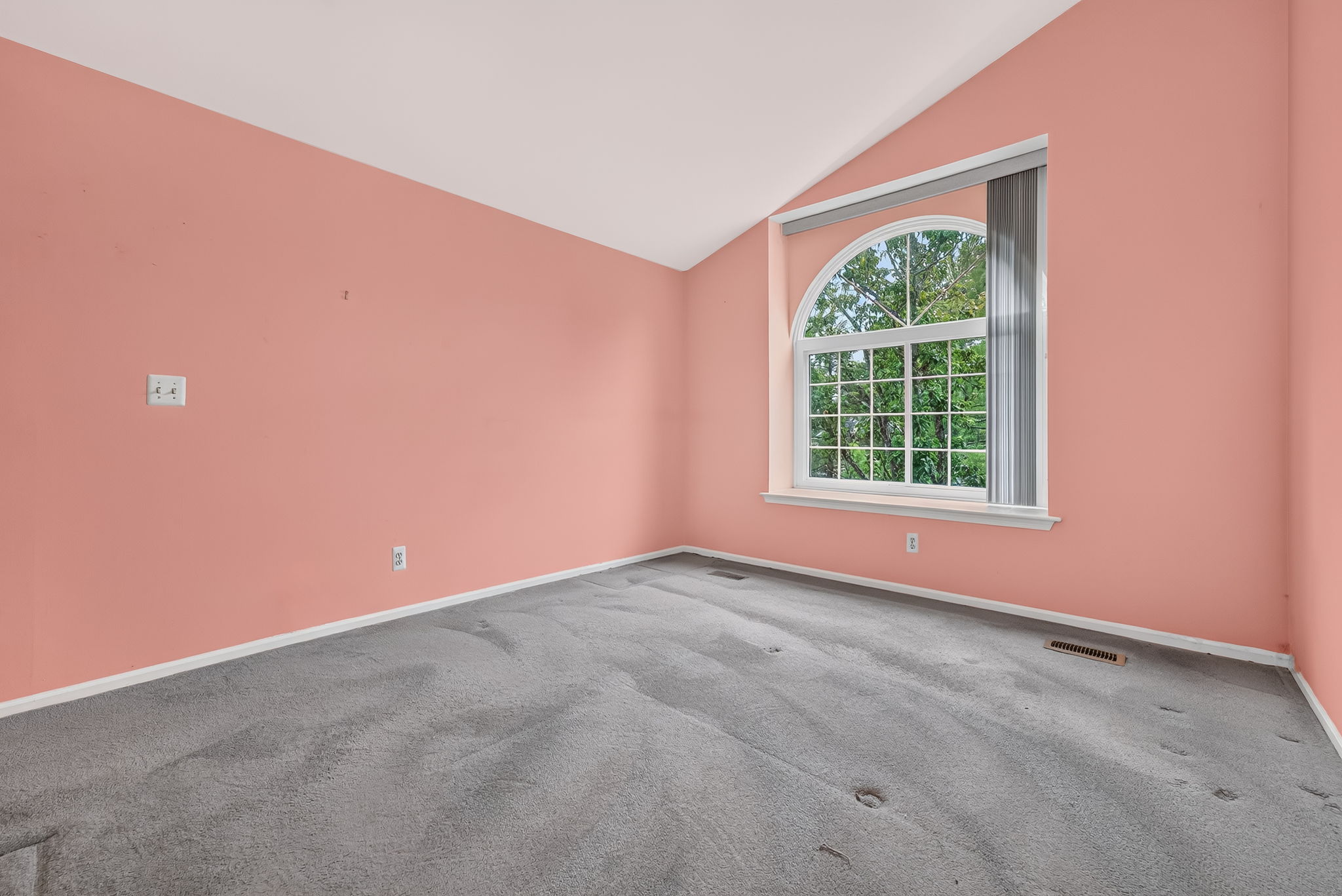 PRIMARY BEDROOM A vaulted ceiling and arch-top window highlight the private primary suite, complete with two closets and an en suite bath.