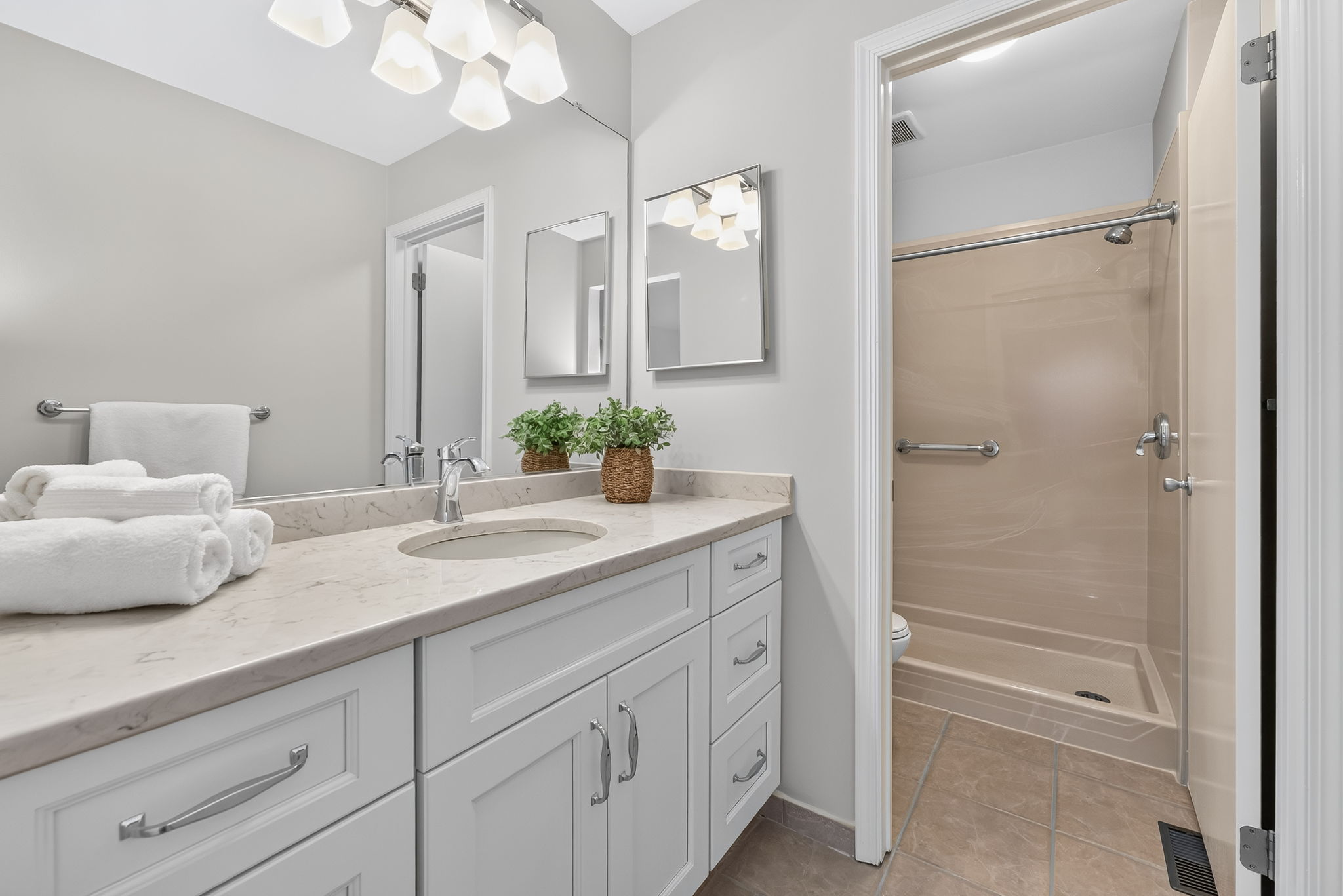 EN SUITE BATH Designed with a spa-like feel, the bath features a Shaker vanity with quartz countertop, high gloss marble-like acrylic walk-in shower and ceramic tile flooring.