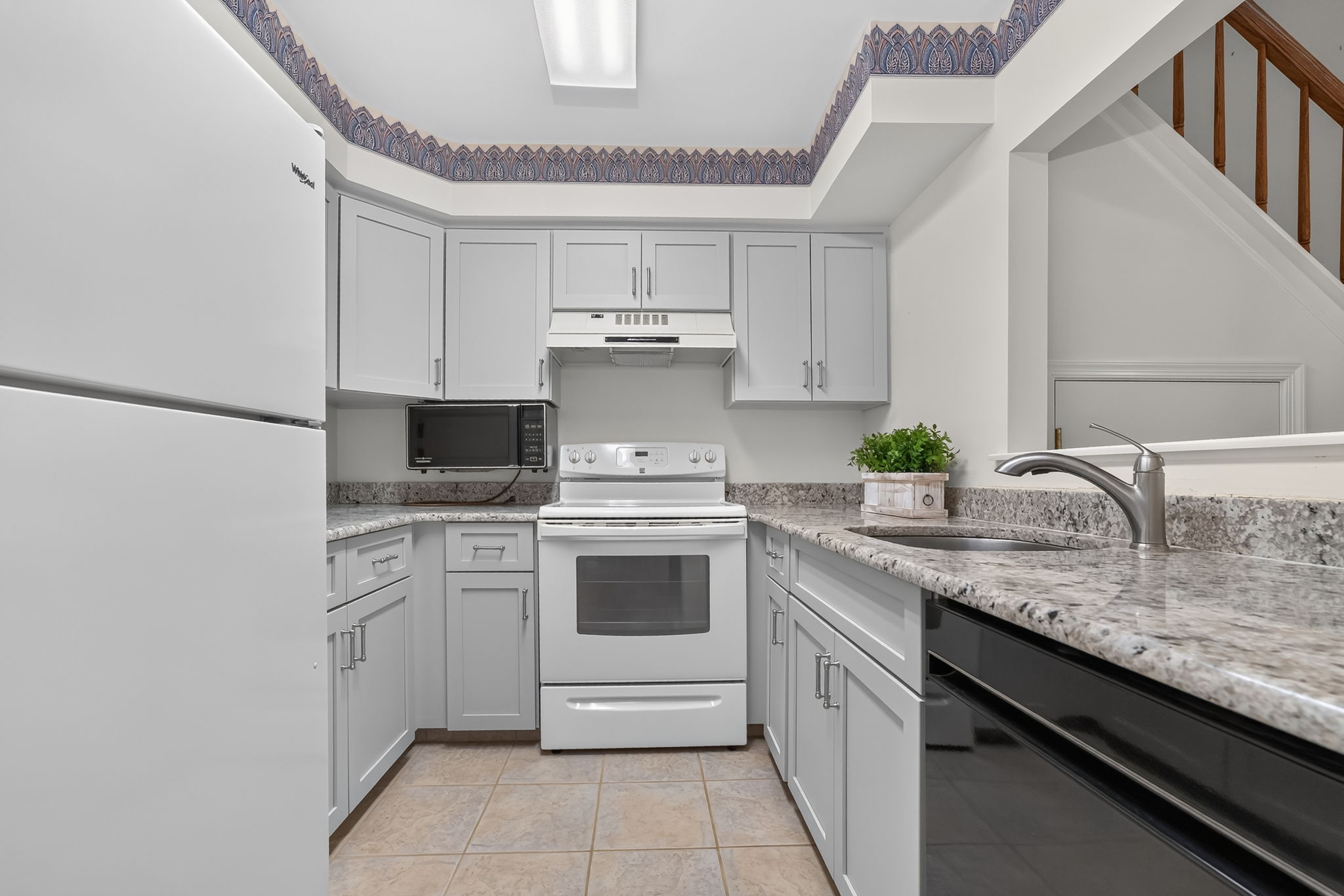 KITCHEN The tastefully renovated kitchen features Shaker cabinetry, granite countertops and ceramic tile flooring.