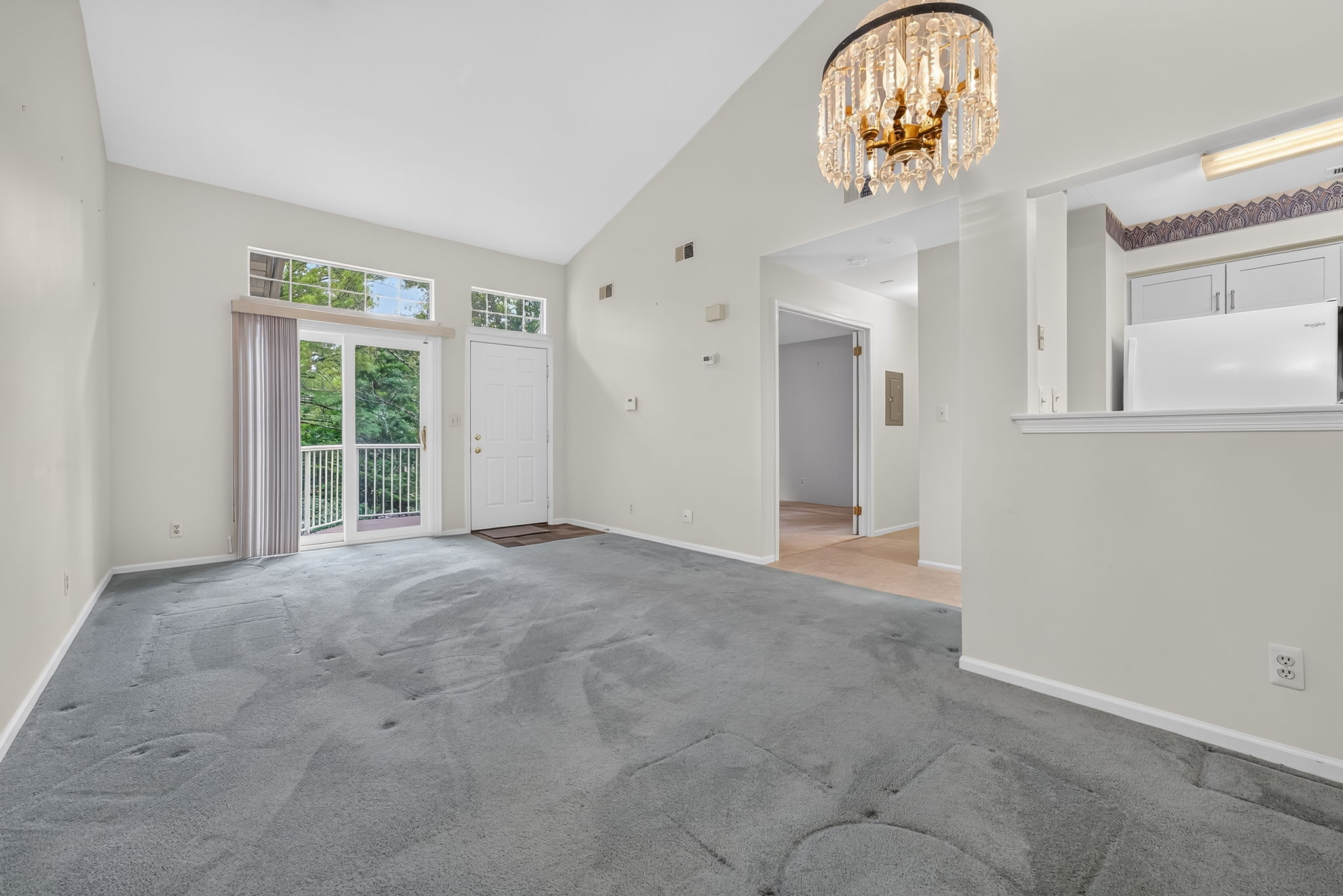 LIVING/DINING ROOM The open-concept main level feels bright and spacious, enhanced by a vaulted ceiling and glass slider leading to a private composite deck—an inviting spot for morning coffee and relaxation. Deck access to a convenient storage closet.
