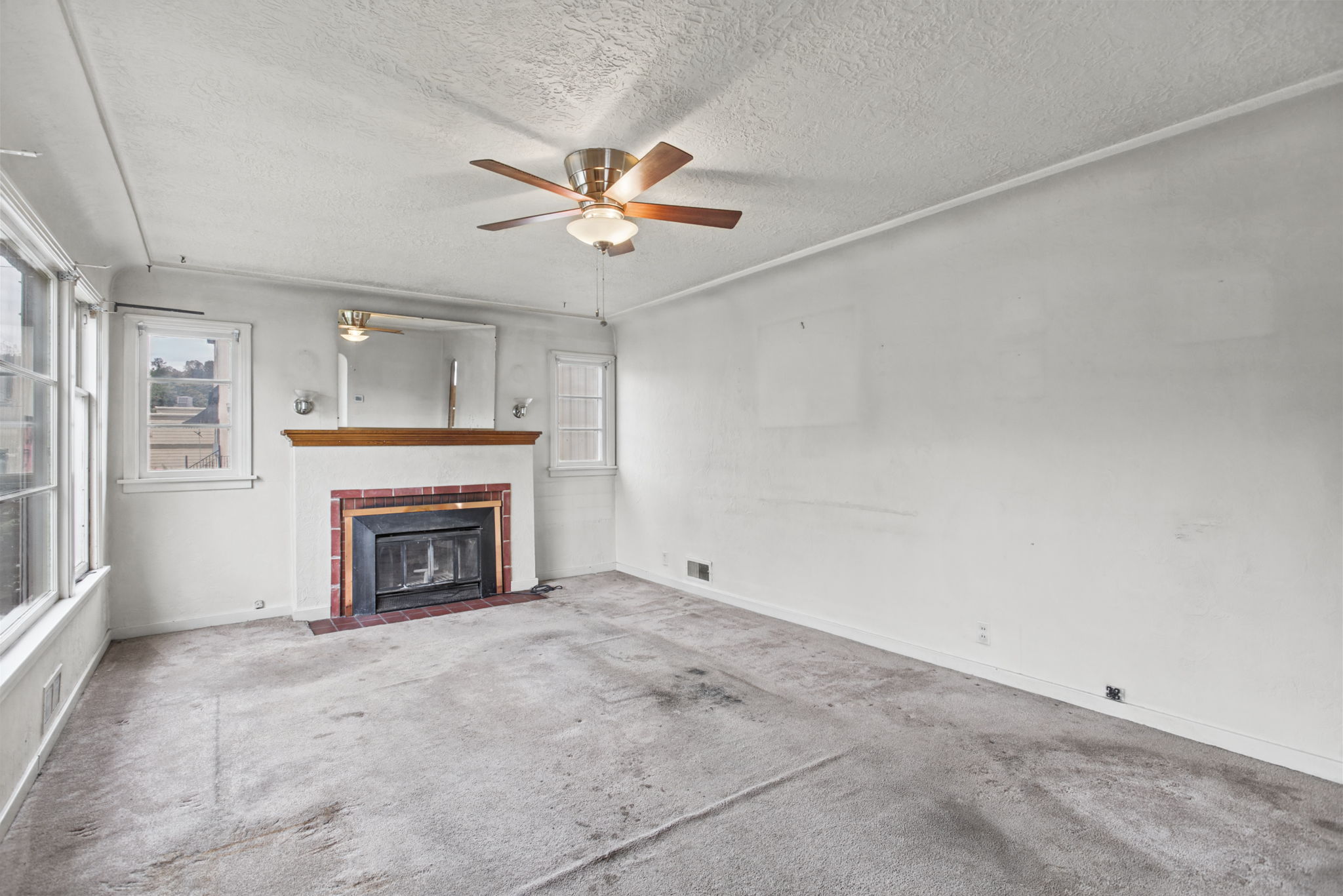 Living room with tile-surround fireplace, wood mantel and coved ceiling.