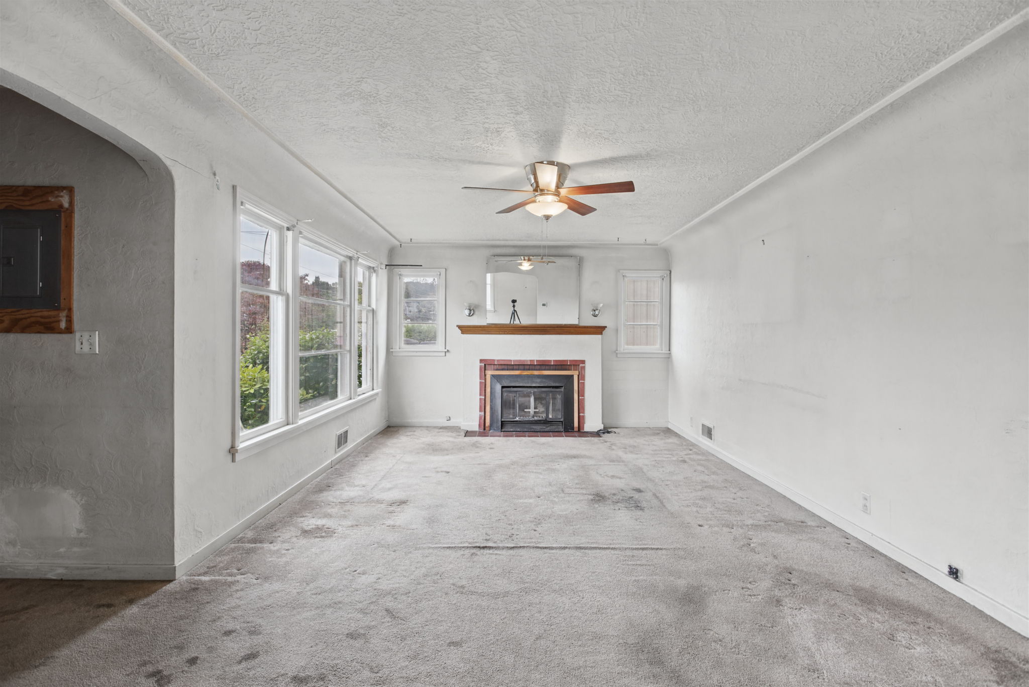 Long living-room view highlighting the fireplace, windows and 1940s architectural details.
