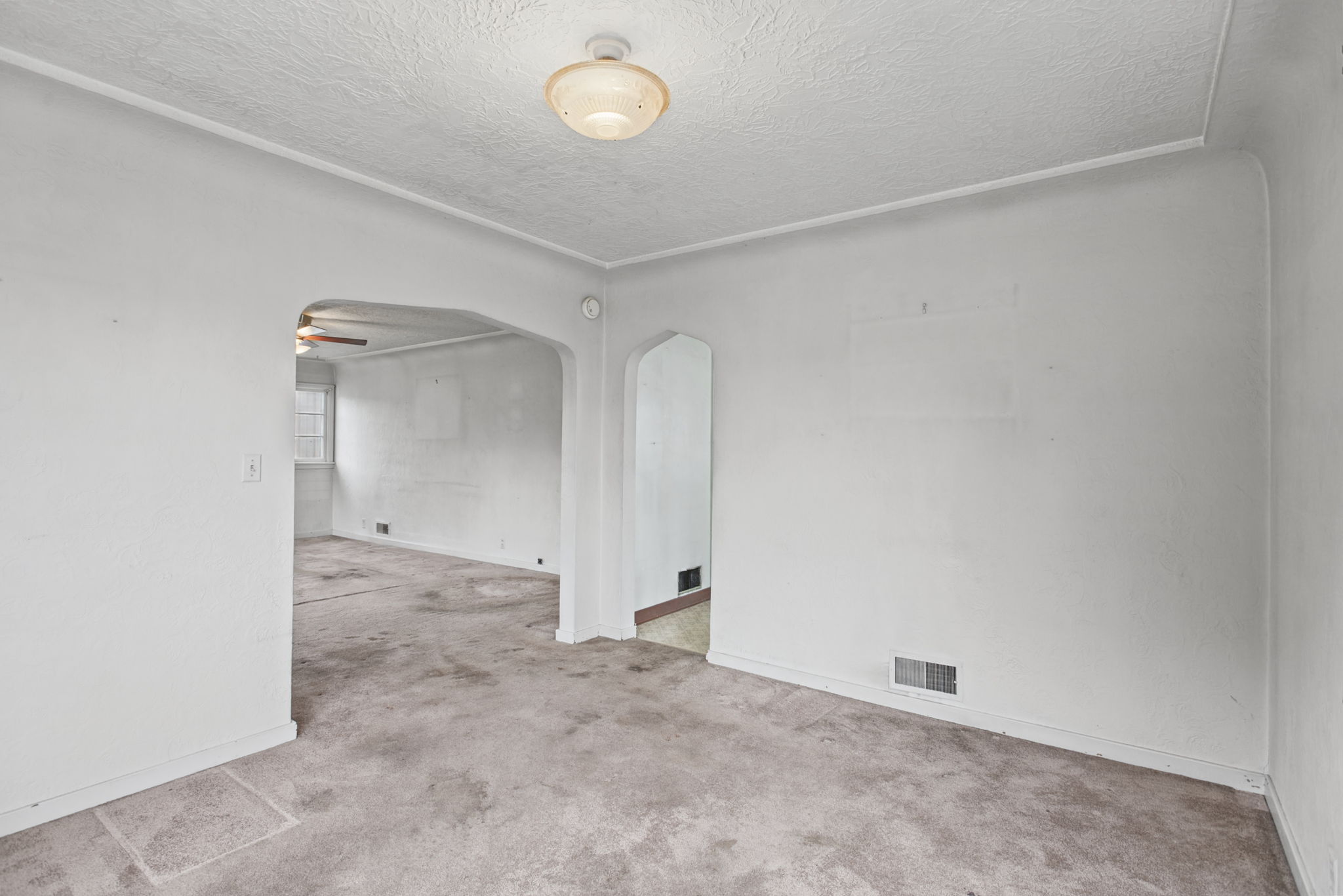 Reverse view highlights the room’s coved ceiling and arched openings.