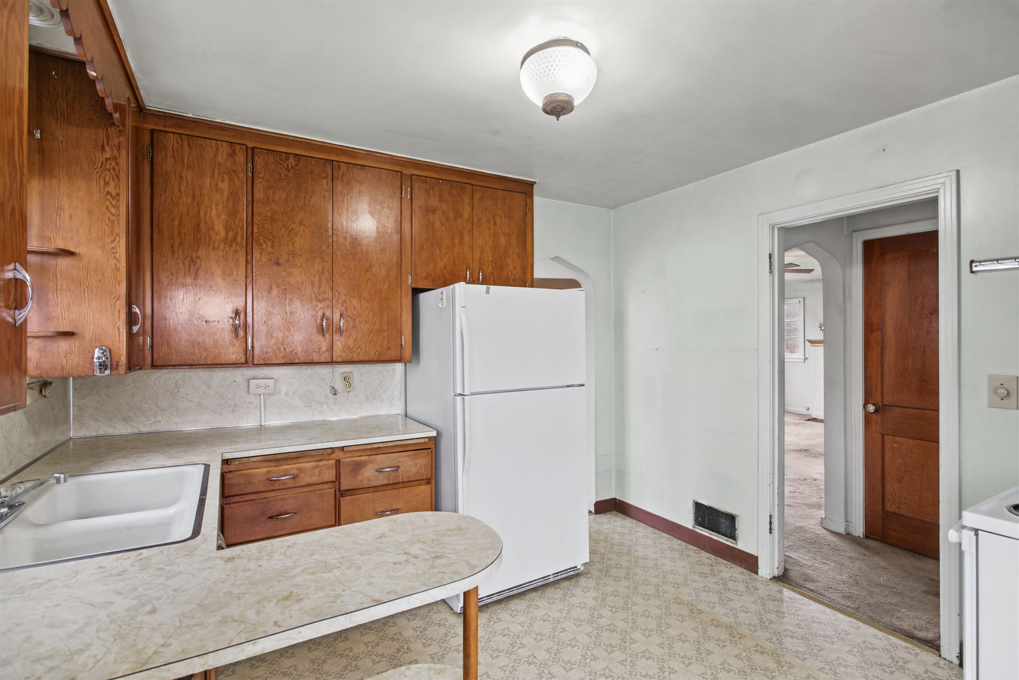 Reverse kitchen view showing the cabinetry, curved counter and connection back toward the dining room.