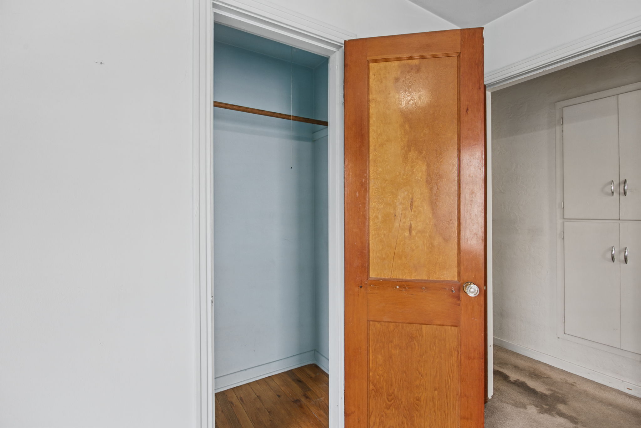 Hardwood flooring visible inside the bedroom closet; extent and condition beneath the carpet elsewhere are unknown.