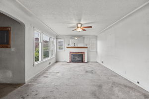 Long living-room view highlighting the fireplace, windows and 1940s architectural details.