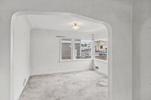 Formal dining room framed by a broad arched opening and corner windows.