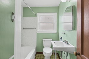 Main-floor full bath with tub/shower, pedestal sink and vintage medicine cabinet.