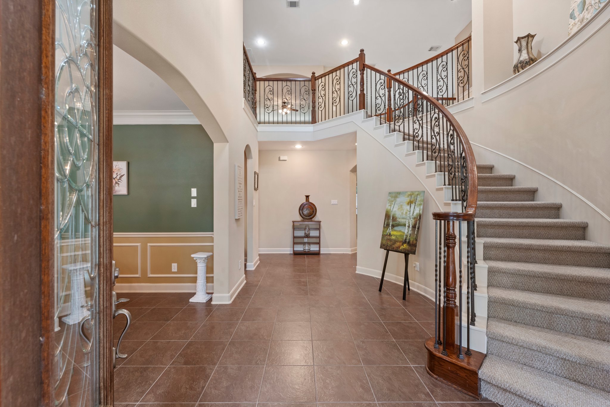 Stunning 2 story entry with soaring ceilings, spiral staircase, Juliet balcony, decorative art niches, and coat closet.