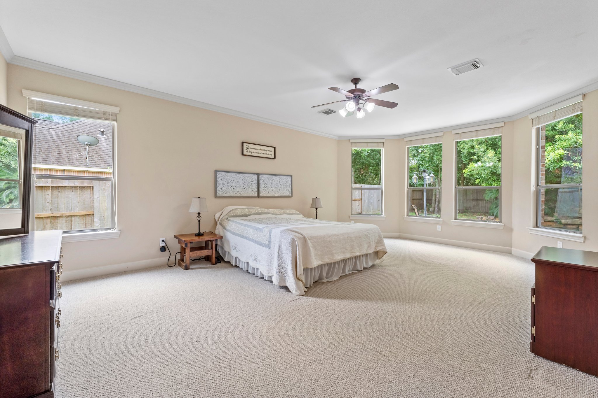 Spacious primary bedroom downstairs with bay windows that provide a relaxing sitting area with a beautiful view of the palm lined pool.