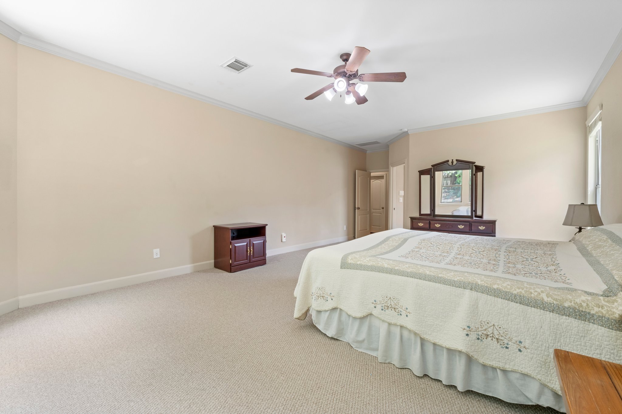 View of primary bedroom with crown molding, ceiling fan, and a California King bed showing how spacious the room is.