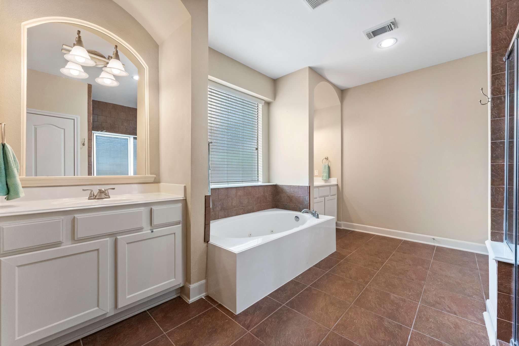 Primary bath includes walk-in shower with bench, jetted garden tub, and connected large walk-in closet.