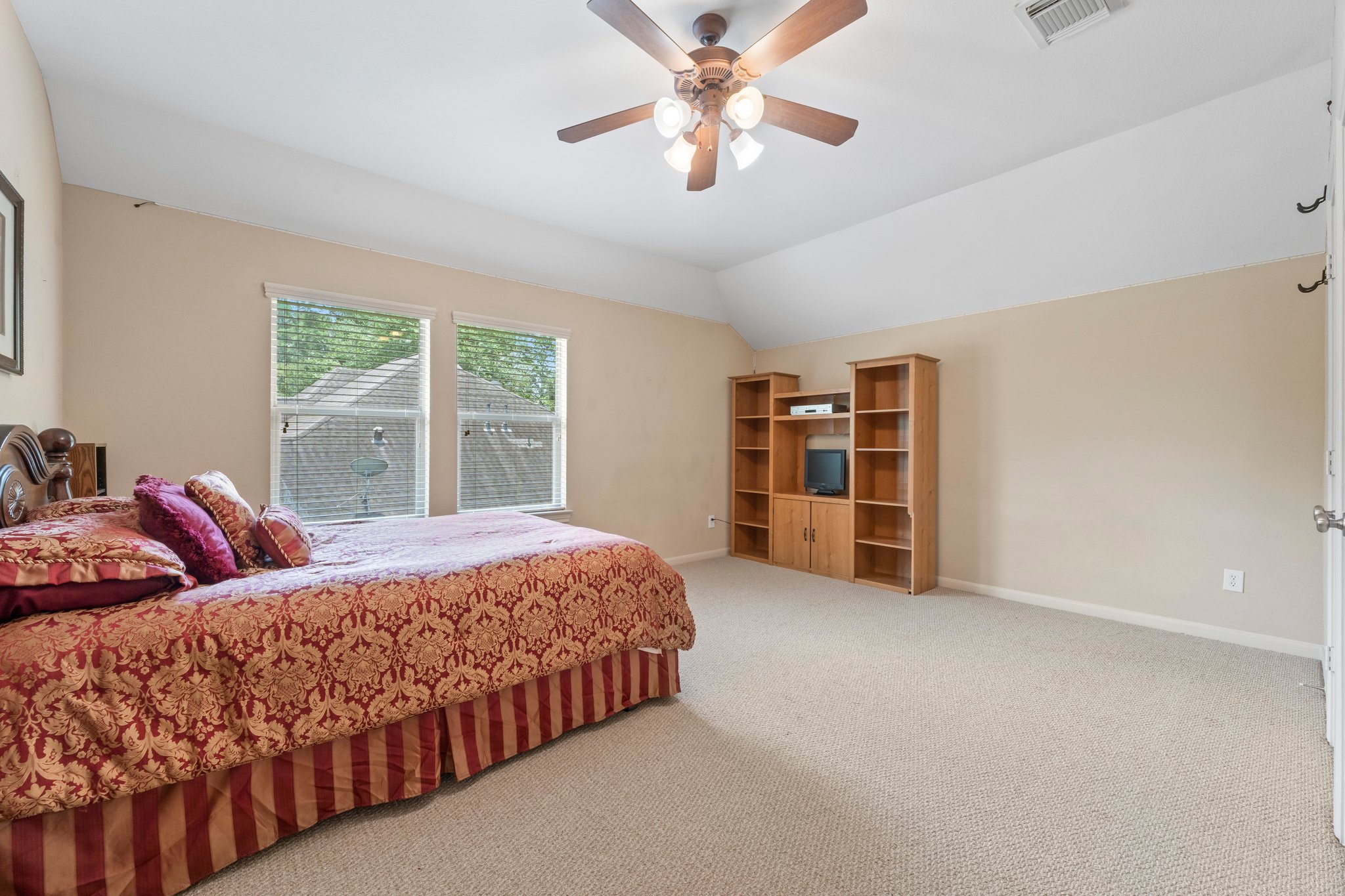 Secondary bedroom with large windows, ceiling fan, double walk-in closet, attic access, and full bath access door.