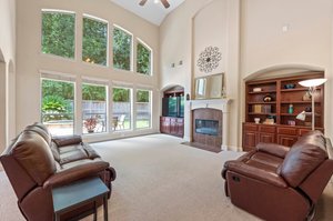 Family room features Berber carpeting, 2 story ceiling with fireplace and builtin shelving with storage.