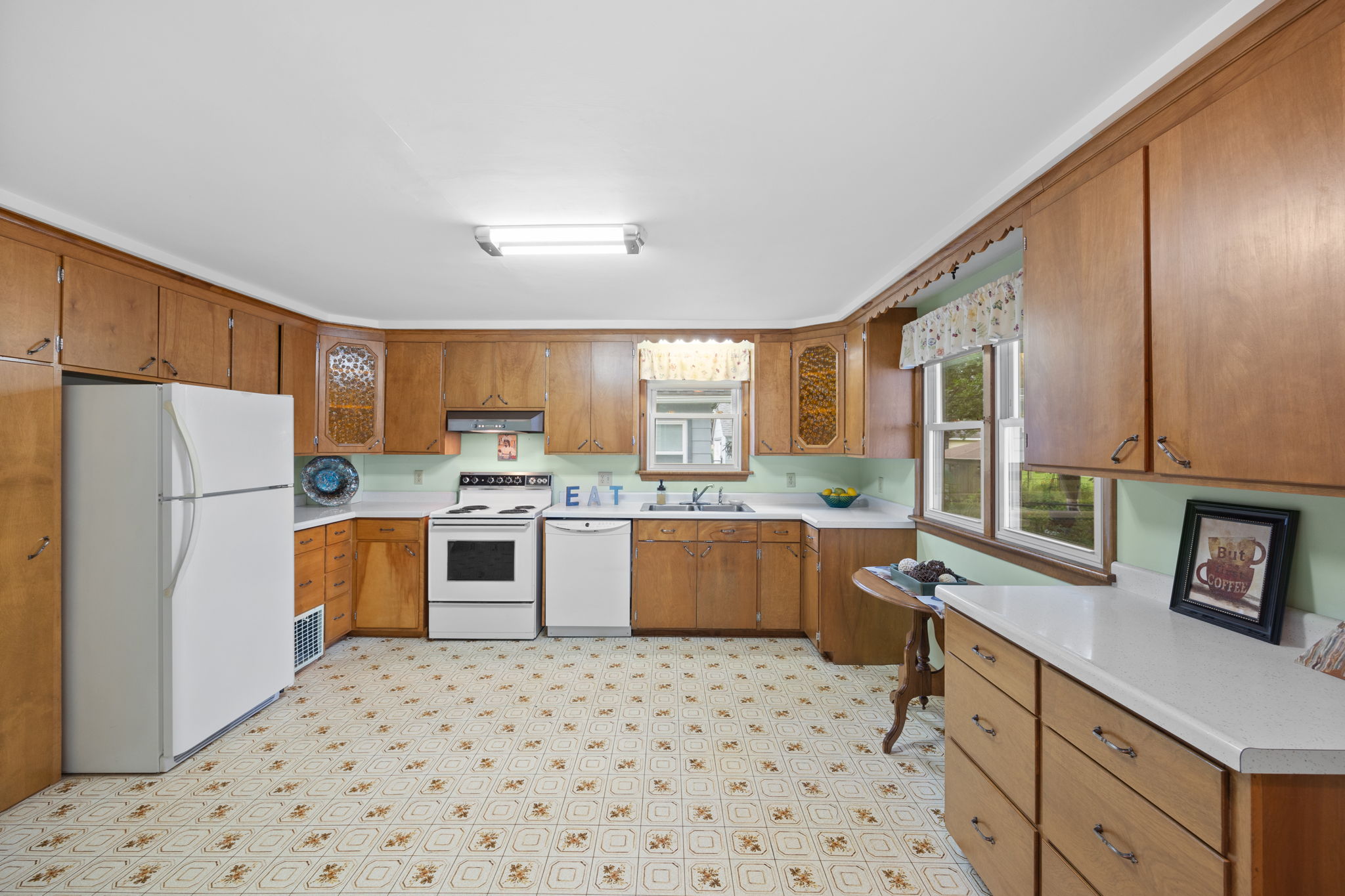 The custom cabinets include deep drawers and a tall pantry cabinet as well as corner cabinets with decorative glass fronts.