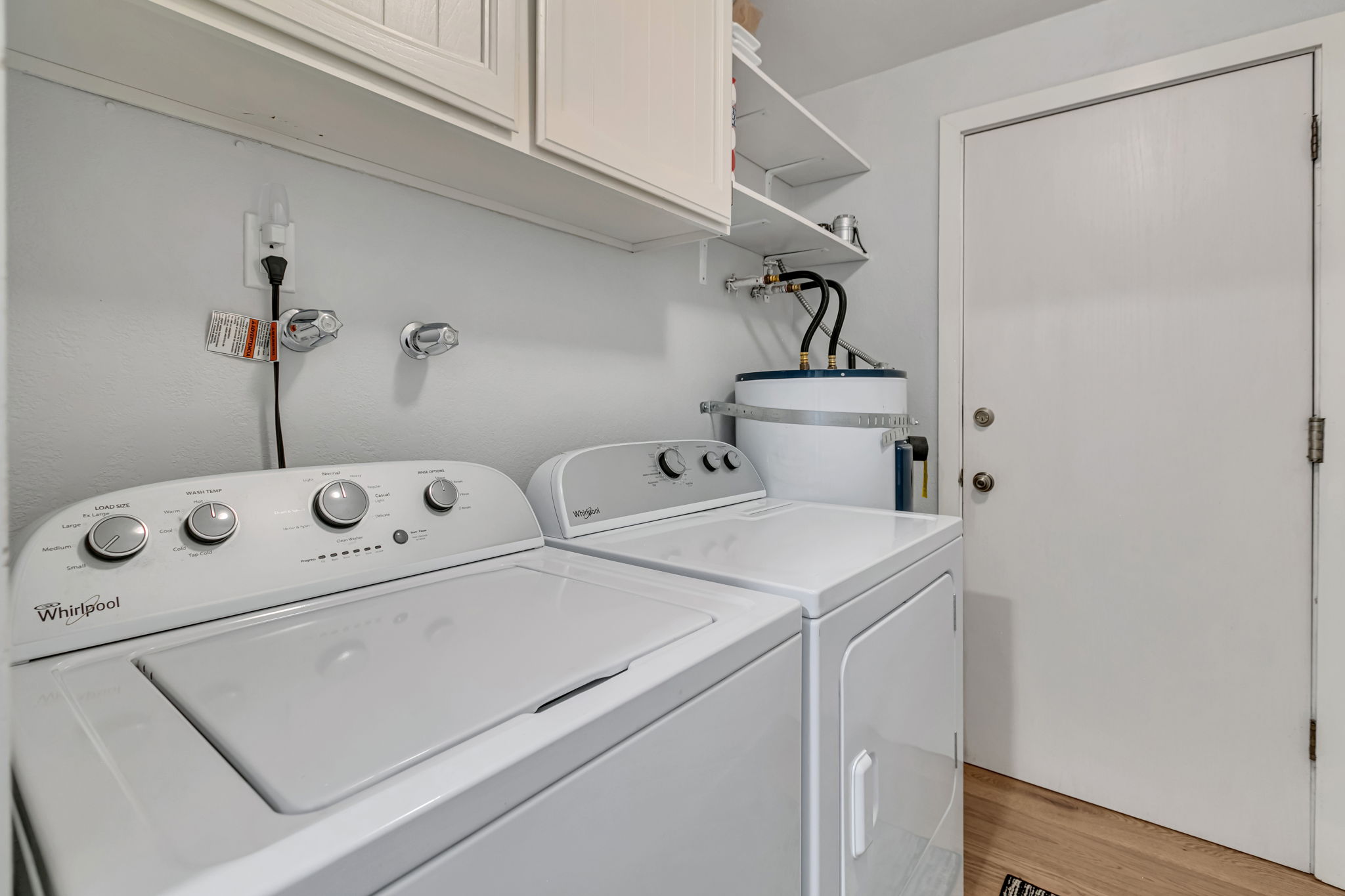 Laundry/mudroom between the garage and kitchen with a full-size washer, dryer, and storage.