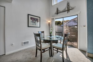Vaulted dining area with large upper window and a sliding door to the patio.