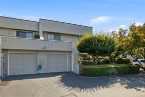 Attached one-car garage plus an additional parking space beside the hedge.