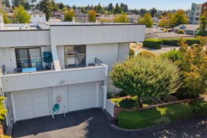 Aerial view highlights the end-unit setting, private balcony, attached garage, and green side yard.