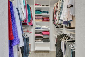Walk-in closet with built-in shelving and double hanging space.