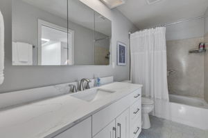 Updated full bath with quartz counters and a large mirrored medicine cabinet.
