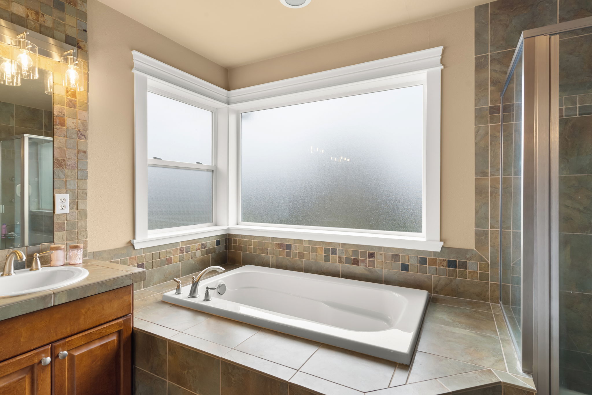 Primary ensuite highlights a generous soaking tub with tile detail.