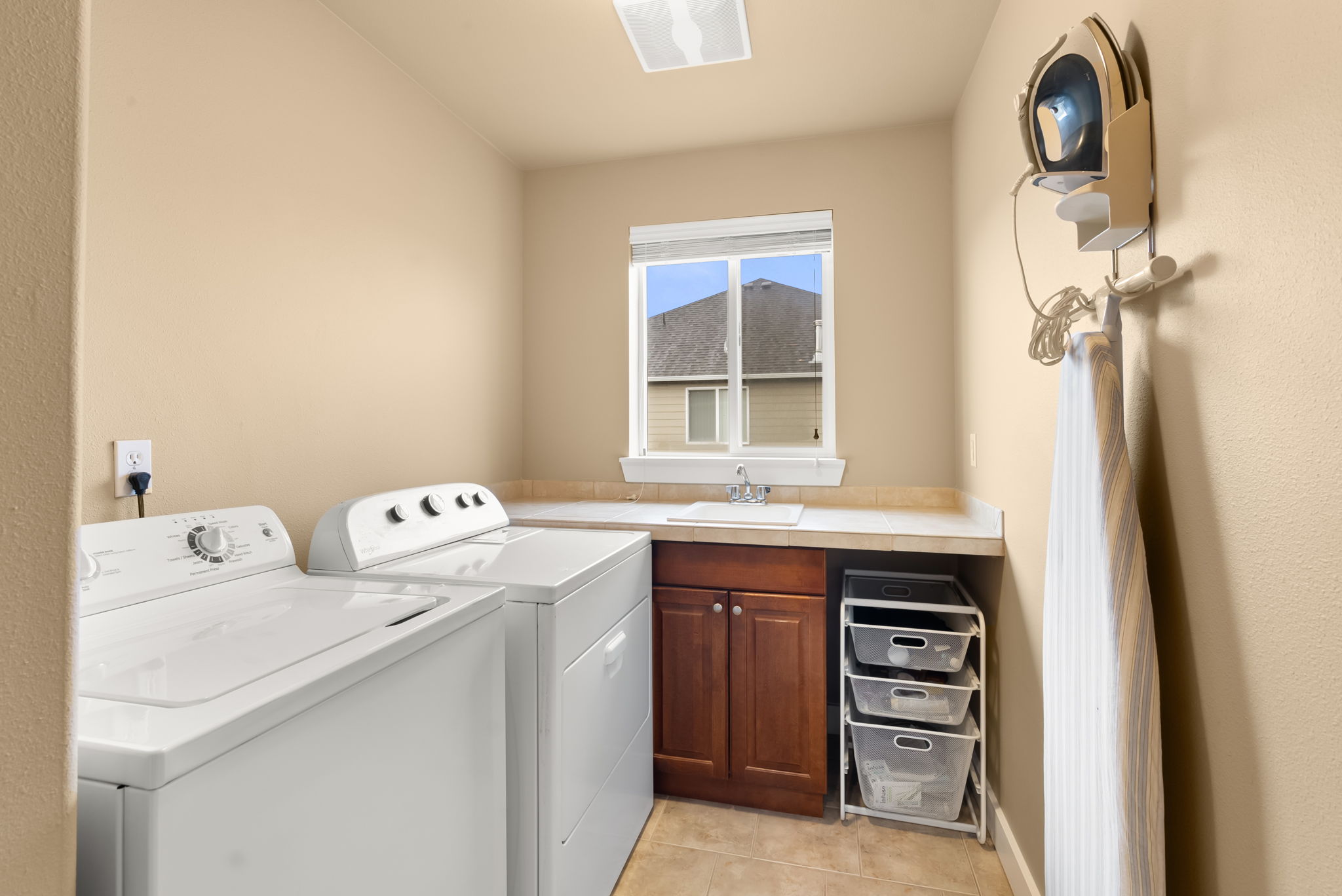 Large laundry room with tile finishes and utility sink, ideally positioned upstairs by the bedrooms.