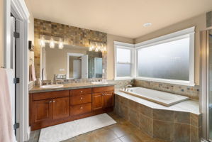 Spa-inspired primary bath with tiled soaking tub and two-sink vanity.