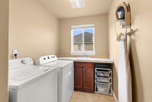 Large laundry room with tile finishes and utility sink, ideally positioned upstairs by the bedrooms.