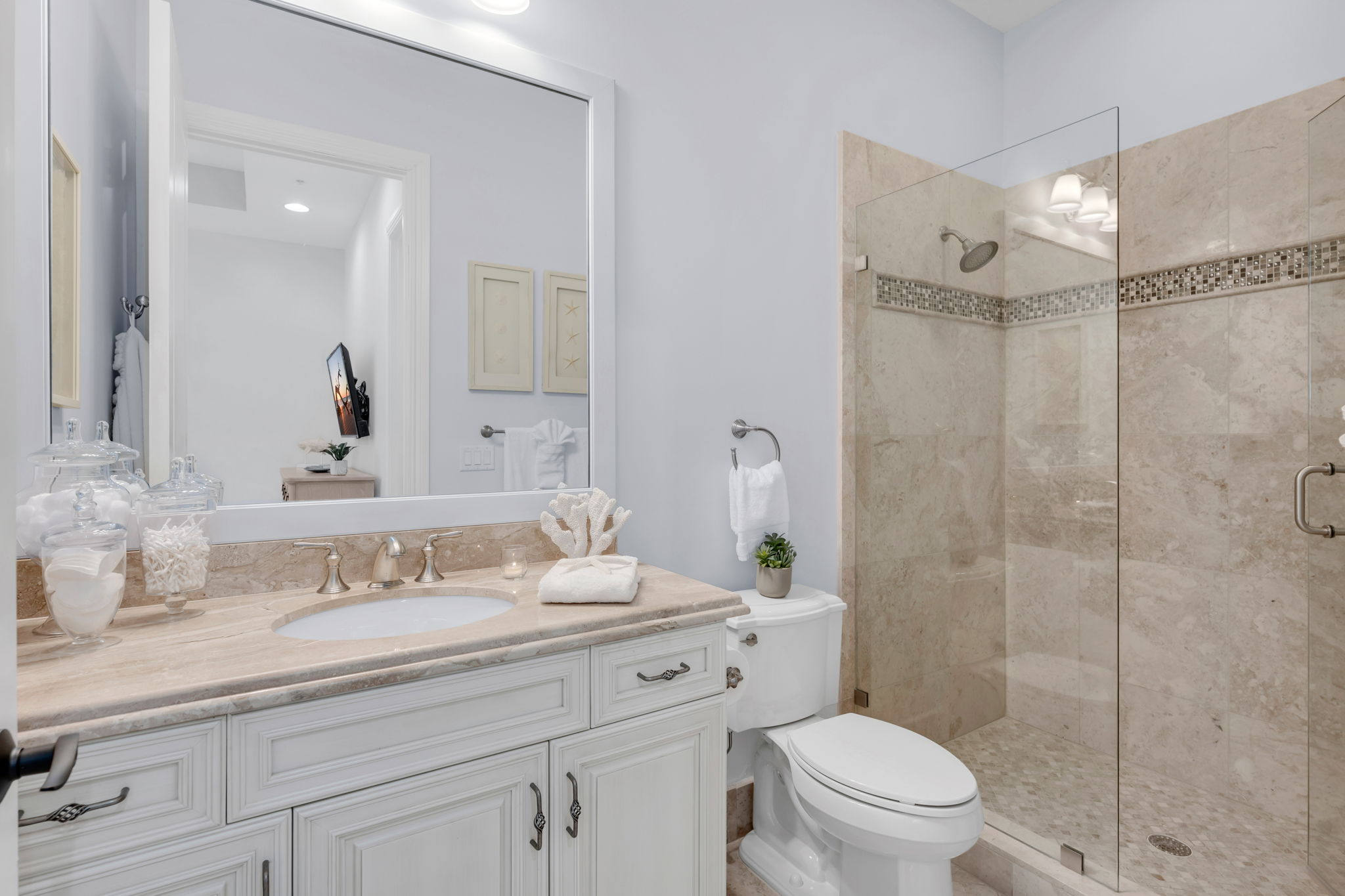 Guest bathroom with spacious vanity and frameless walk-in shower.