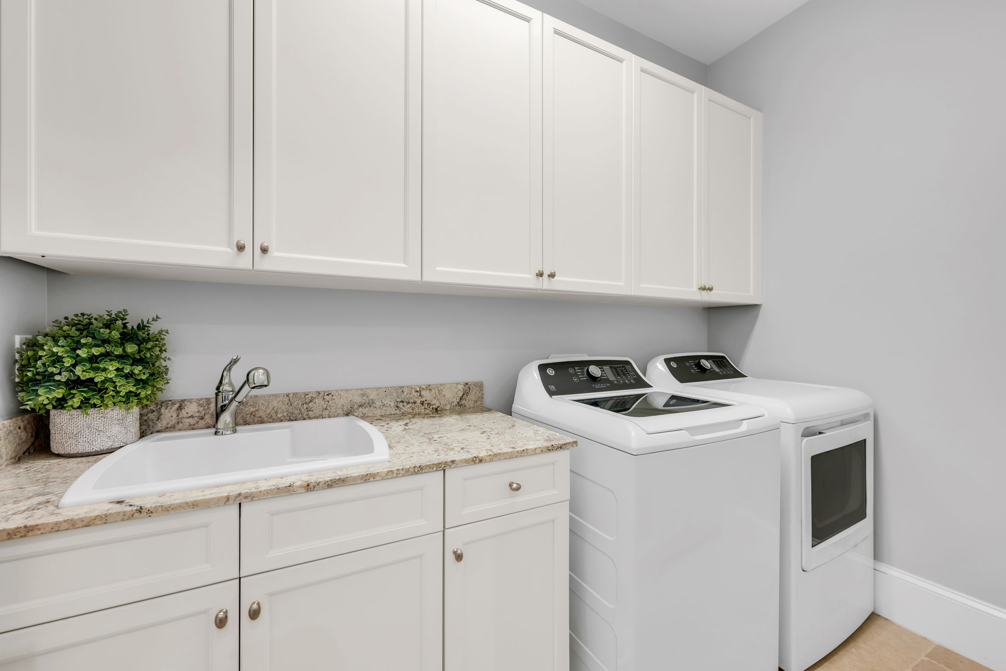 Laundry room with granite countertops and brand new General Electric washer/dryer units.