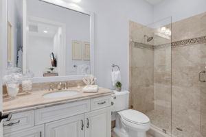 Guest bathroom with spacious vanity and frameless walk-in shower.