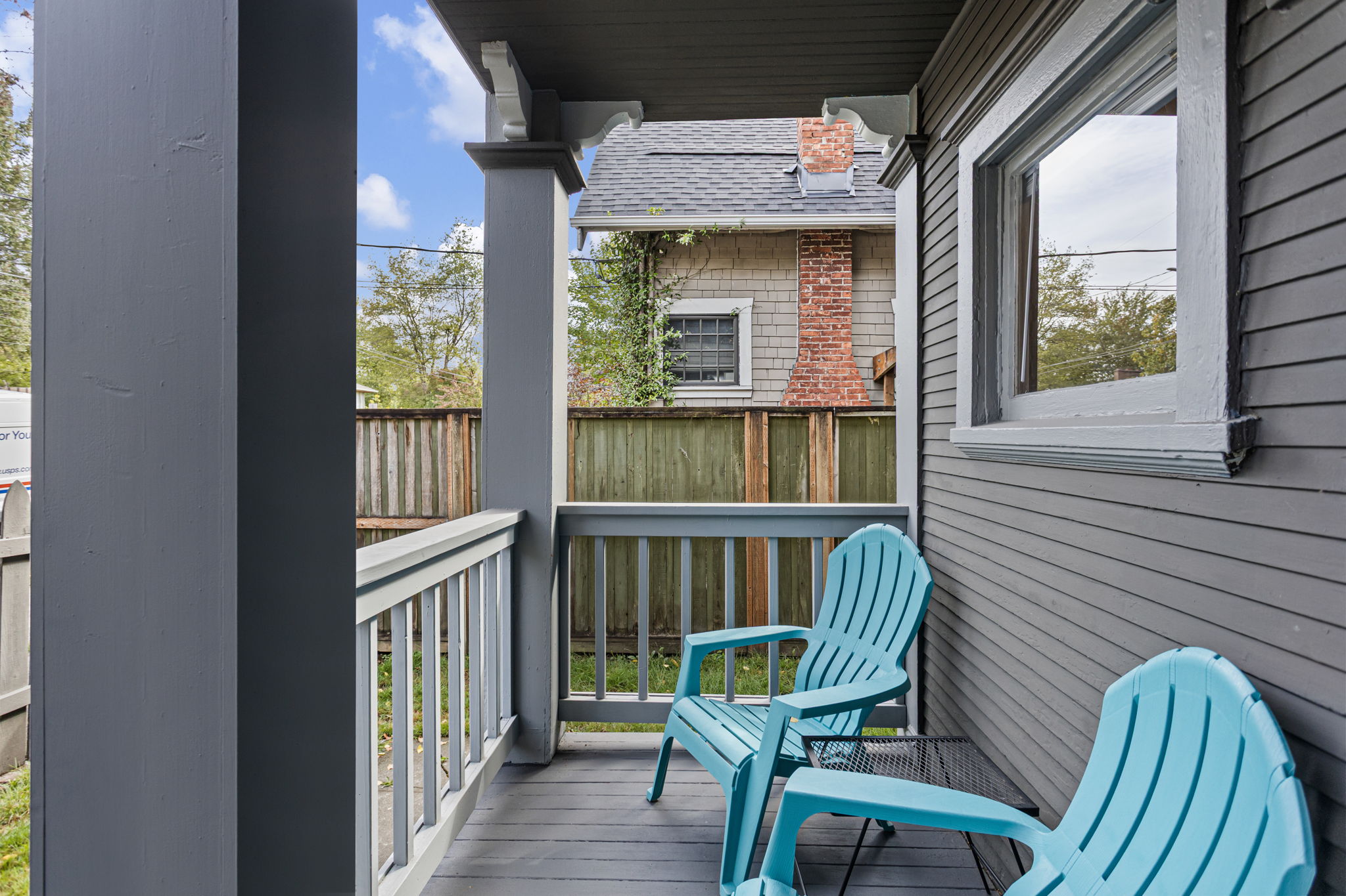 The shared covered porch fits two chairs—a small sitting spot just outside the front door.