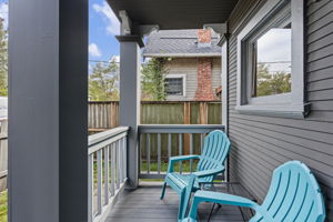 The shared covered porch fits two chairs—a small sitting spot just outside the front door.