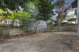 The shared backyard is fully fenced and shaded by mature trees, with paved areas for outdoor seating.